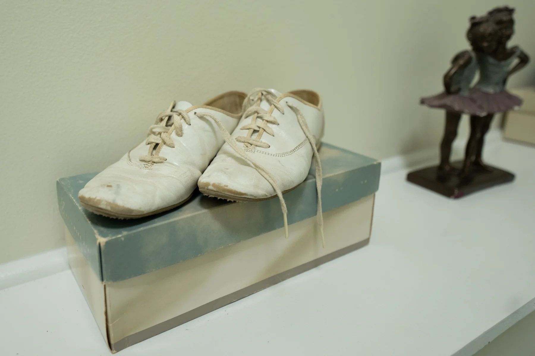 Small dance shoes and a dancer figurine displayed in the studio