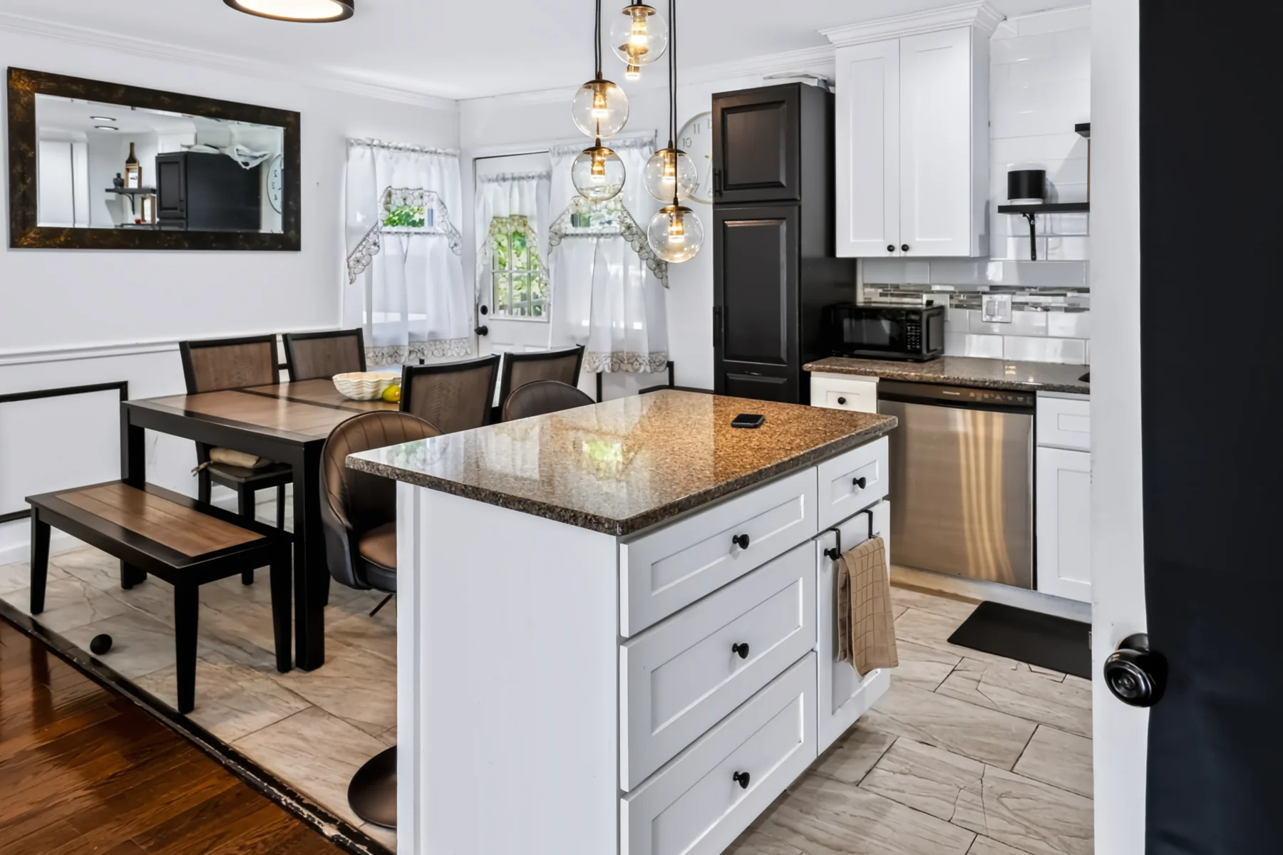Open kitchen and dining area with white cabinets, pendant lights, and hardwood floors