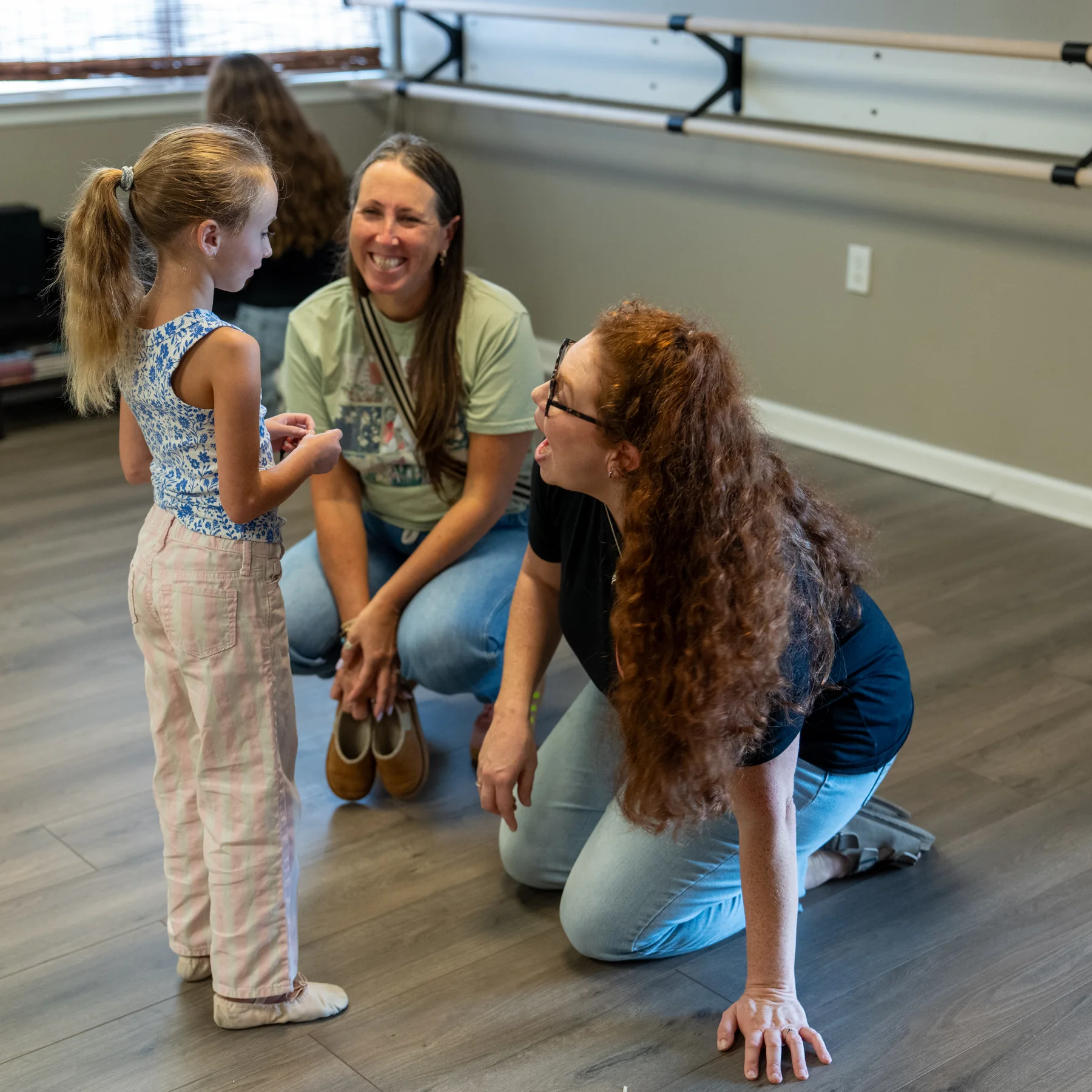 Instructors talking with a young dancer in the studio